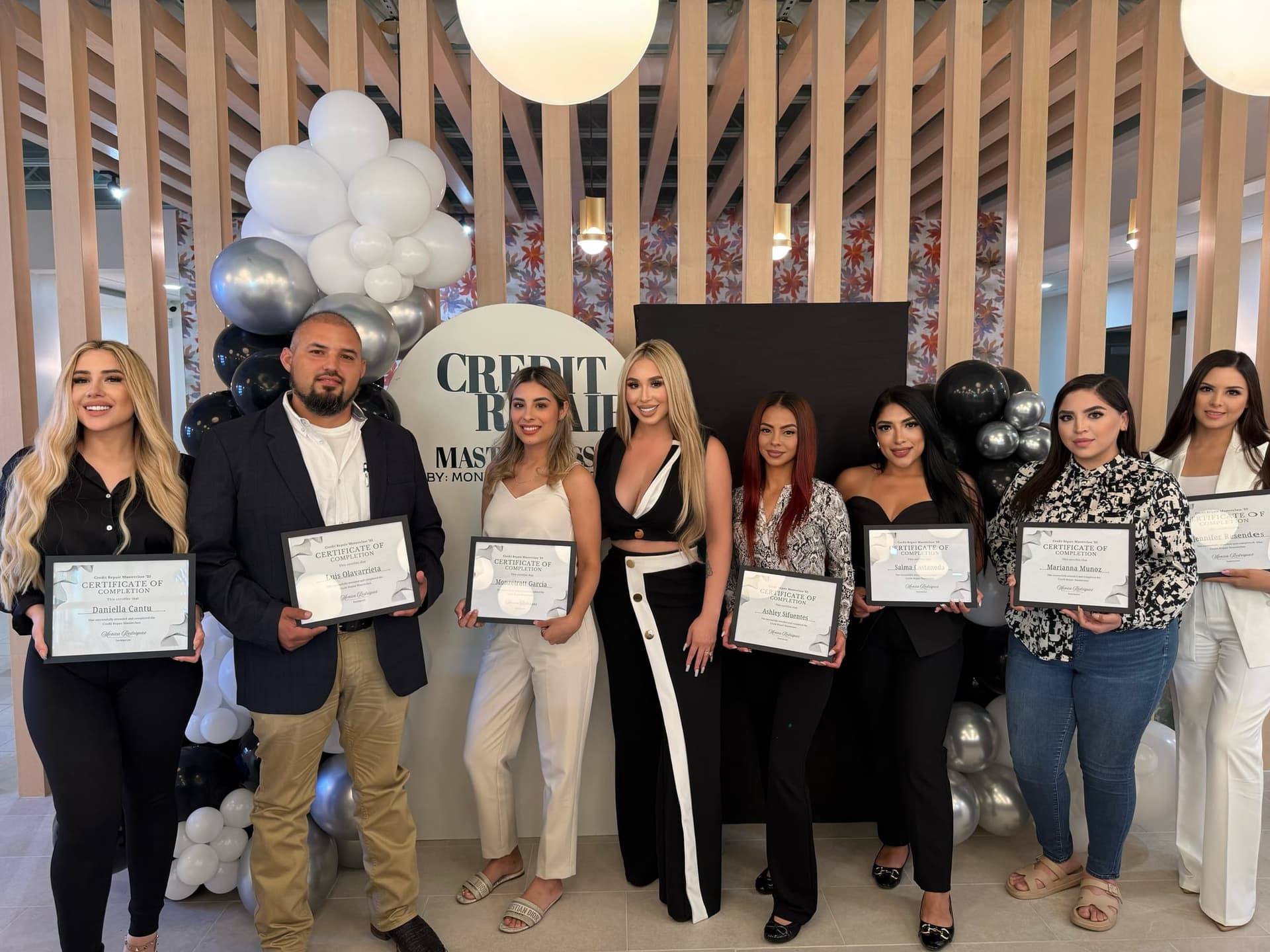 A graduating class holding their Credit Repair Masterclass certificates with Monica Rodriguez